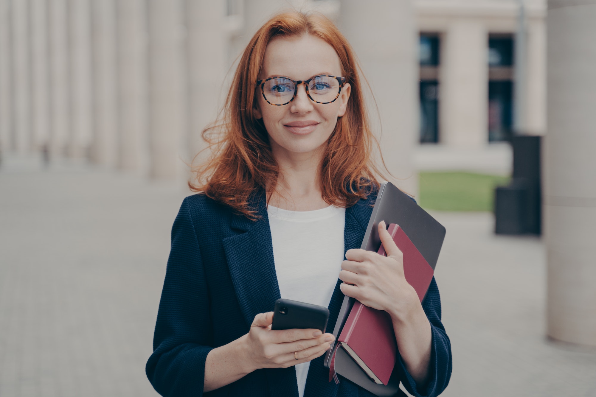 confident-beautiful-red-haired-female-business-consultant-holding-modern-smartphone-and-laptop.jpg